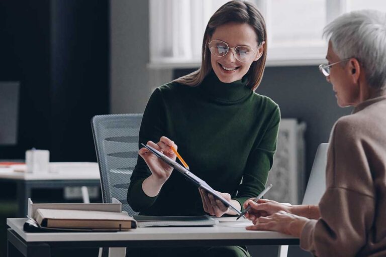 Two adults sitting at a kitchen table discussing paperwork and family finances together.